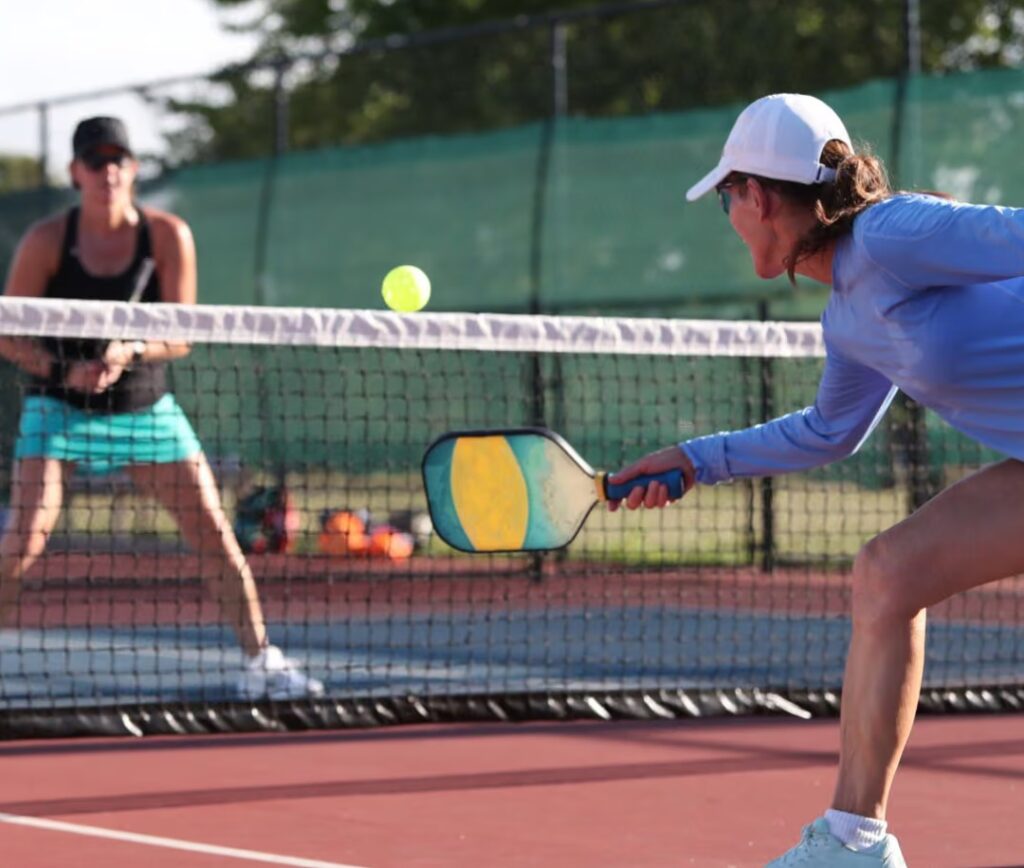two people play pickleball outside.