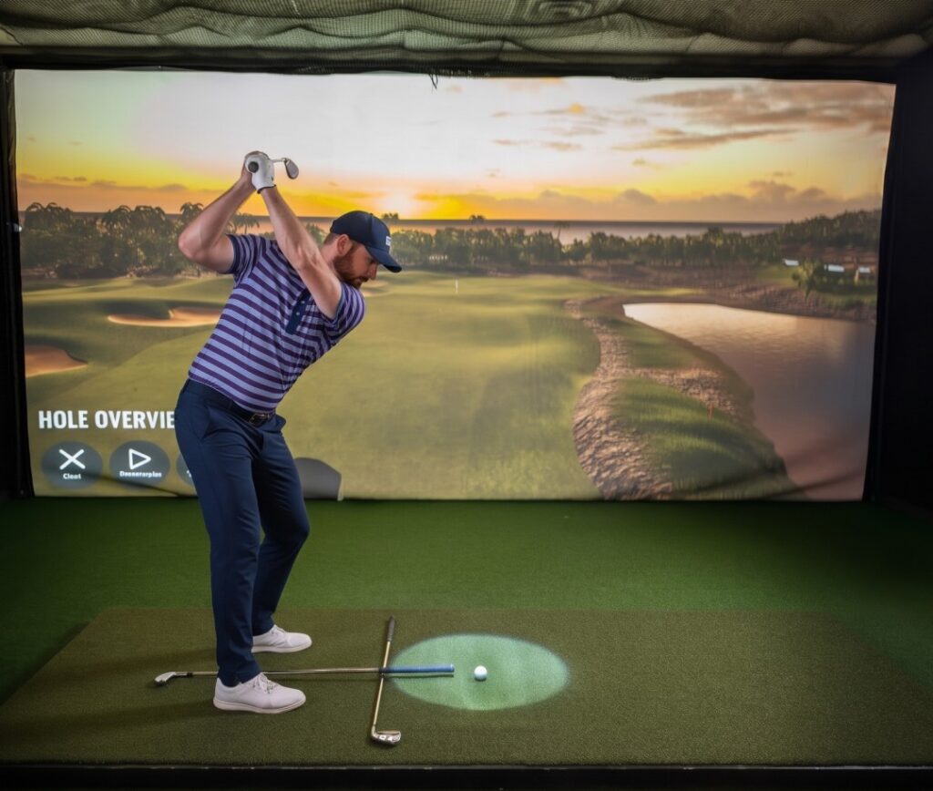 a man swings a club in front of a virtual golf screen.